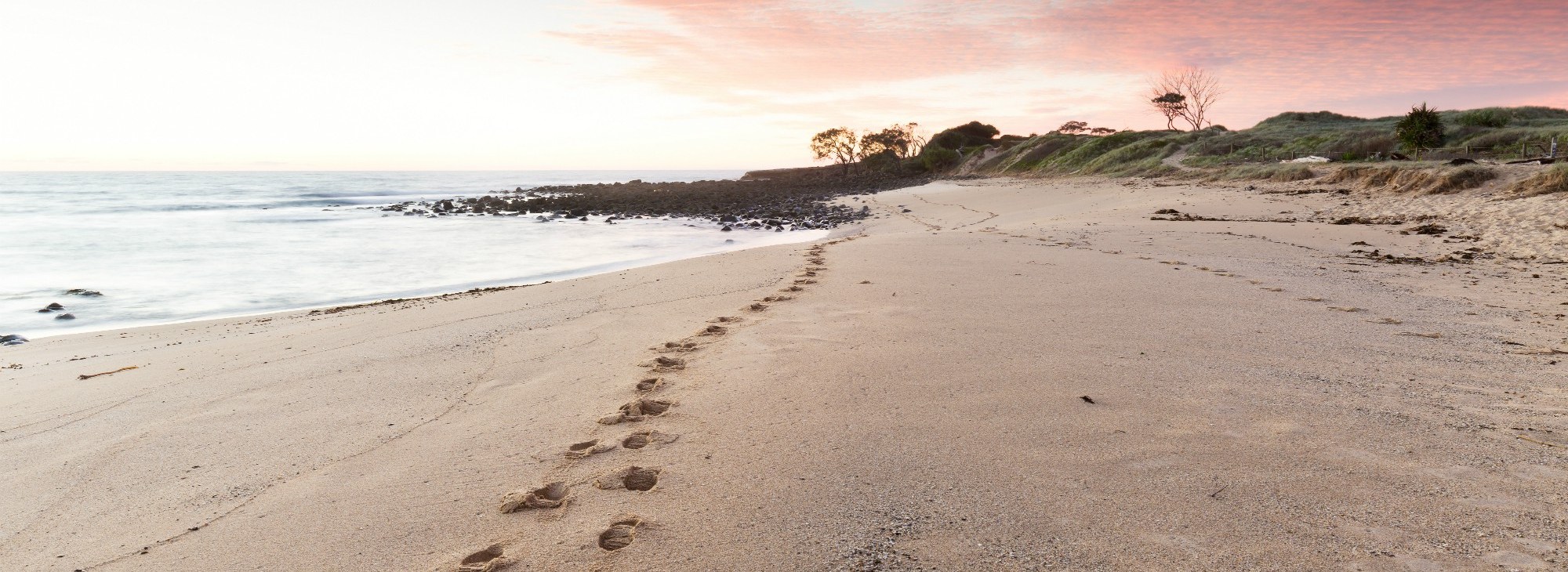 banner image of my footprints on a beach at sunset